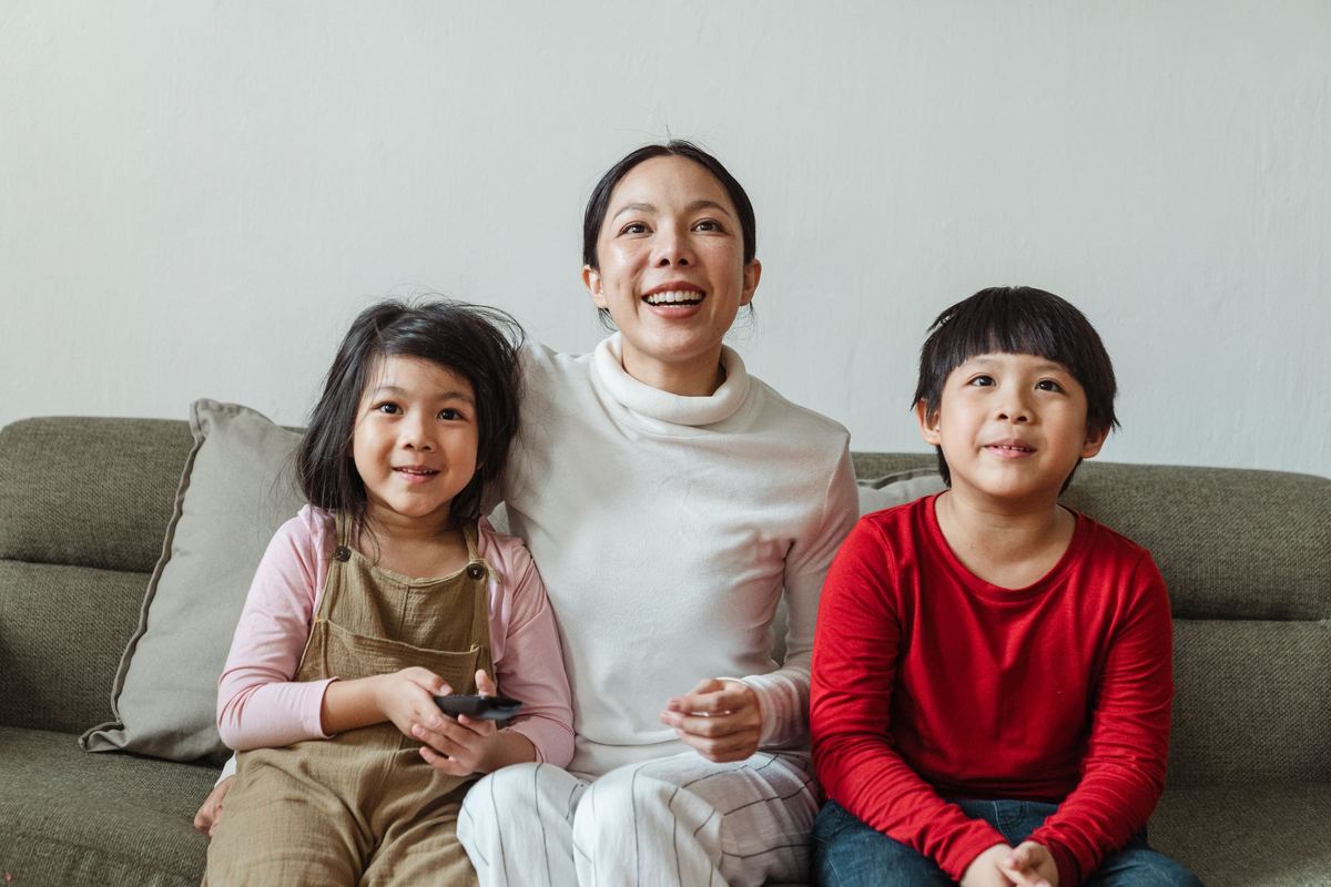 A smiling mother sitting on the couch with her two children.