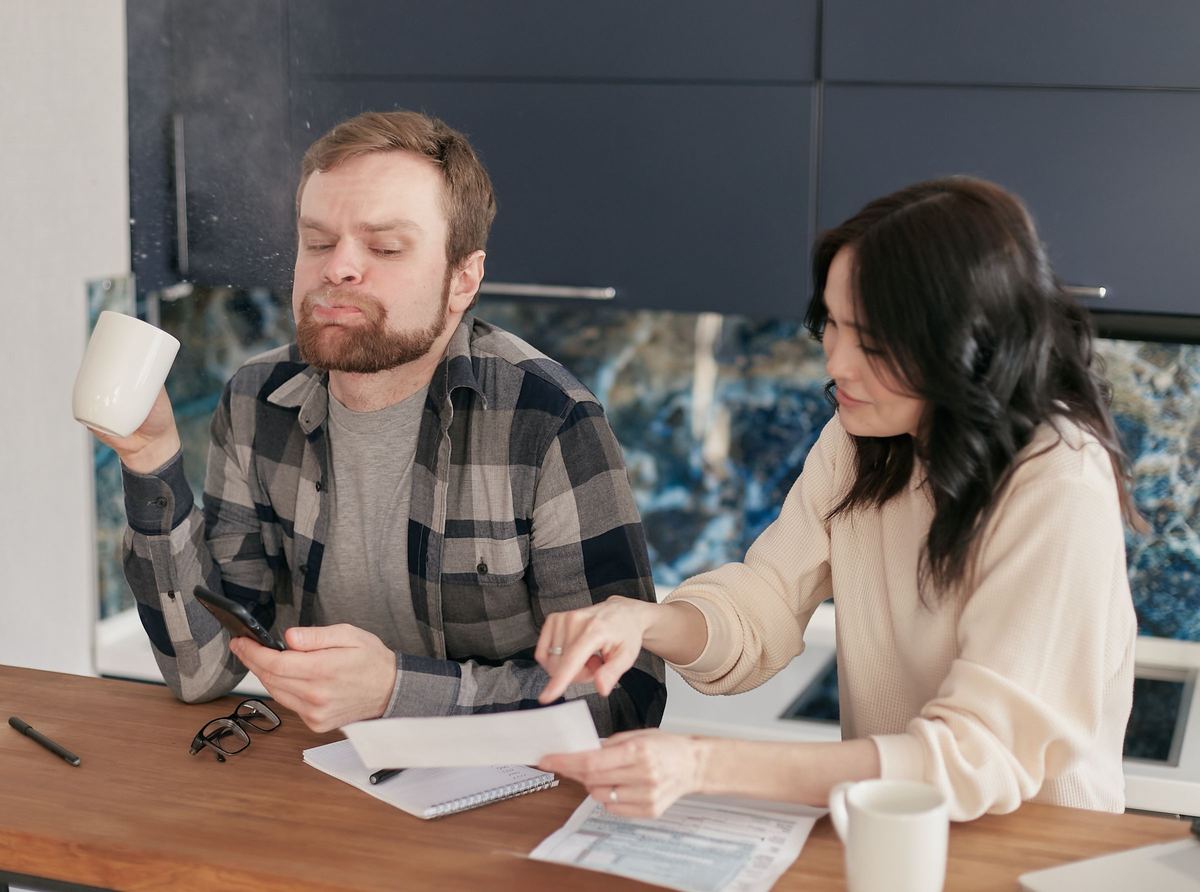 A couple at their kitchen table going over bills and paperwork.