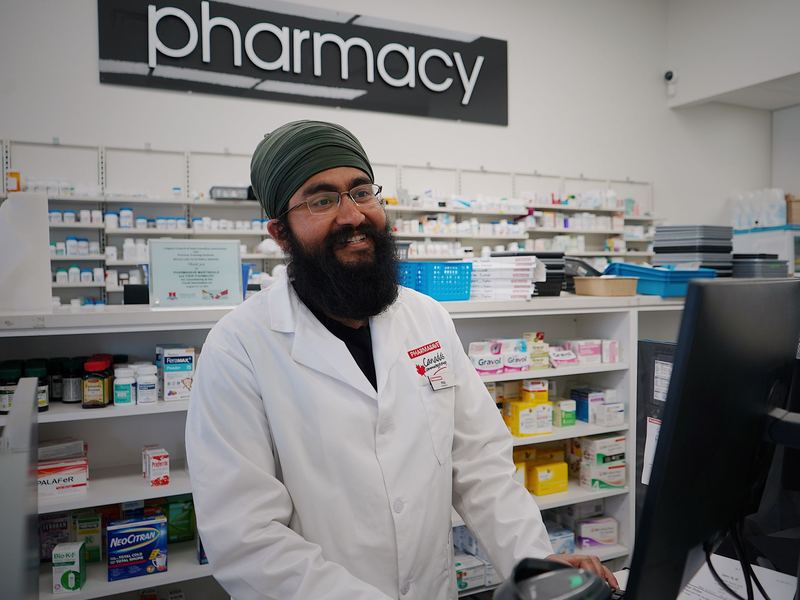 A smiling pharmacist at the counter of a local pharmacy.
