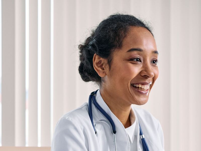 A smiling provider in a white coat with a stethoscope.