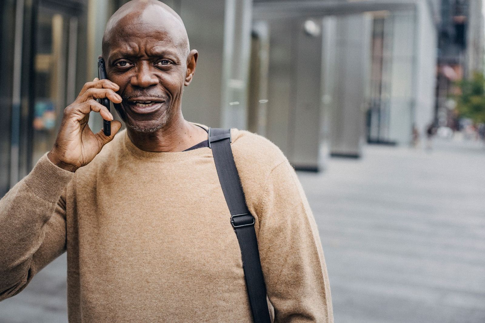 A smiling man talking on his phone on a city street.